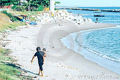 Mother holds her son on the beach to return to the shore after swimming in the sea Editorial Stock Photo