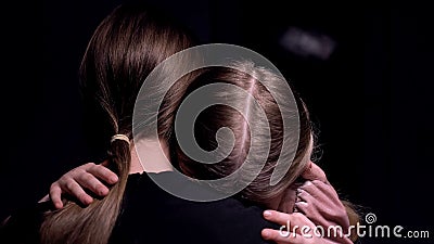 Mother hugging frightened little girl in dark room, victims of mafia, kidnapping Stock Photo