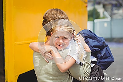 Mother hugging her daughter by school bus Stock Photo