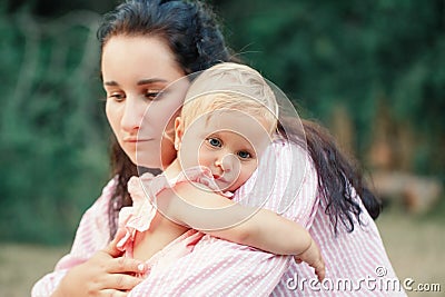 Mother hugging pacifying sad upset toddler girl. Family young mom and tired baby in park outdoor. Bonding attachment relationship Stock Photo