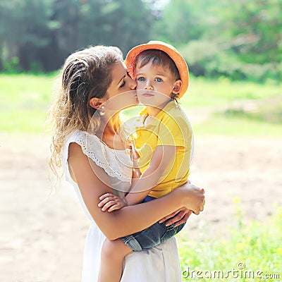 Mother kissing child outdoors in sunny summer Stock Photo