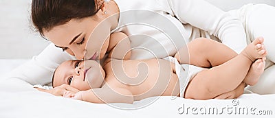 Mother kissing her sweet adorable baby in bed Stock Photo