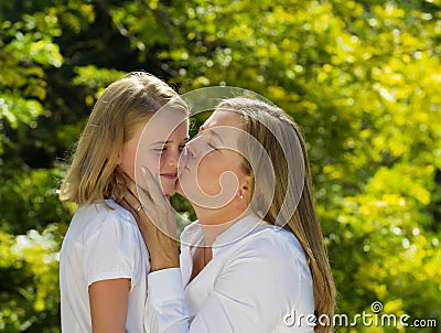 Mother kissing her young daughter on side of face Stock Photo