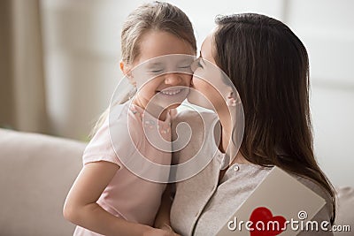 Mother kissing little daughter on cheek, thanking for gift postcard Stock Photo