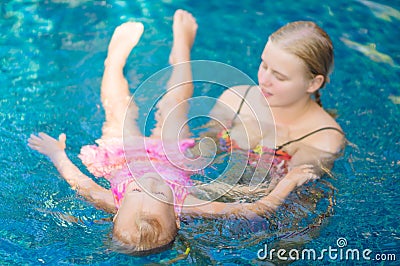 Mother learns daughter to relax in pool water at tropical beach Stock Photo