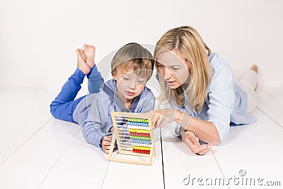 Mother learns to calculate with son on a white floor Stock Photo