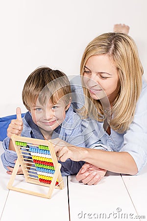 Mother learns to calculate with son on a white floor Stock Photo