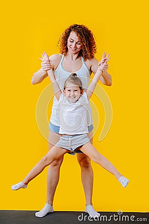 Mother lifting daughter above ground, she moves her legs apart Stock Photo