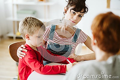 Mother and and little boy in red sweater learn by drawing during ADHD therapy Stock Photo