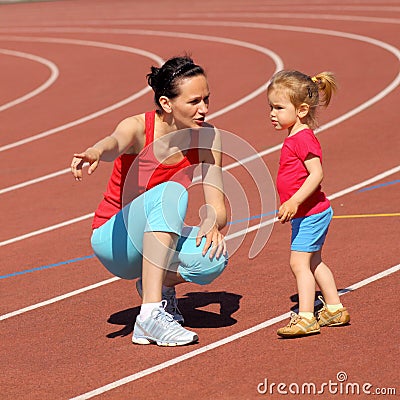 Mother & little daughter running around the stadium. Stock Photo