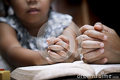 Mother and little girl hands folded in prayer on a Holy Bible Stock Photo