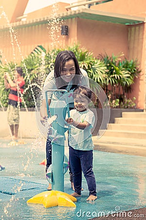 Mother and little girl having fun to play with water in park Stock Photo