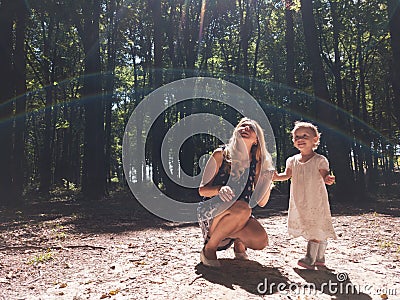 Mother and little girl into the sun light inside the forest Stock Photo