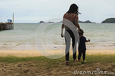 Mother and little her son is holding hand each other at the beach and looking beautiful sea Stock Photo