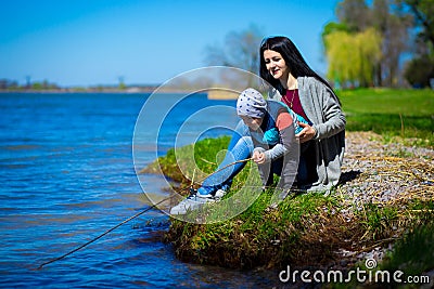 Mother and little son play in fishermen on shore of lake Stock Photo