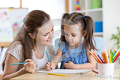 Mother looking how her child daughter drawing a picture Stock Photo