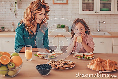 Mother looking little girl drinking orange juice while they having breakfast together Stock Photo