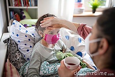 Mother looking after sick small daughter in bed at home, coronavirus concept. Stock Photo