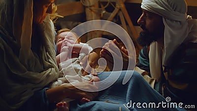 Mary and Joseph with baby Jesus resting in dim barn Stock Photo