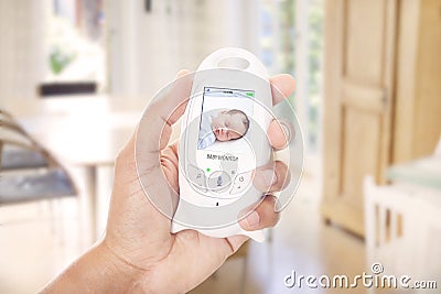 Mother mnitoring sleeping baby through baby monitor Stock Photo