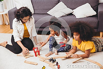 Mother parent playing with children learning to solve puzzle toy at home apartment. Nanny looking or childcare at living room Stock Photo