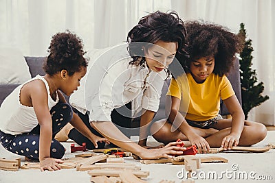 Mother parent playing with children learning to solve puzzle toy at home apartment. Nanny looking or childcare at living room Stock Photo