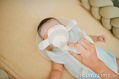 Mother playing with baby lying in a crib, 6 months old, top view, hidden face Stock Photo