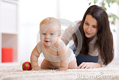 Mother playing with creeping on floor baby Stock Photo
