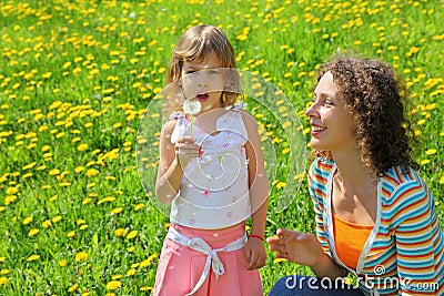 Mother plays with girl which breath on dandelion Stock Photo