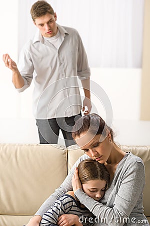 Mother protecting her daughter from angry father Stock Photo