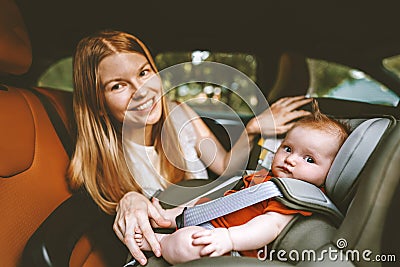 Mother putting baby in safety car seat happy family Stock Photo