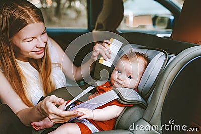 Mother putting baby in safety car seat mom and child together family Stock Photo