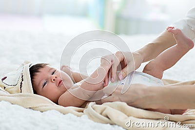 Mother putting diaper on her happy baby in nursery Stock Photo