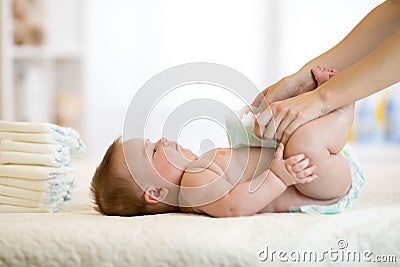 Mother putting diaper on her baby in nursery Stock Photo