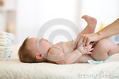 Mother putting diaper on her baby in nursery Stock Photo