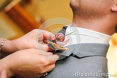 Mother putting a flower in the buttonhole of the groom dress Stock Photo