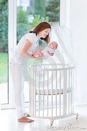 Mother putting her newborn baby to sleep in crib Stock Photo