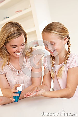 Mother putting sanitizer on young girl's hands Stock Photo