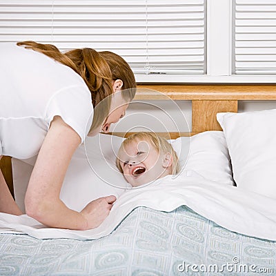 Mother putting talkative son to bed at bedtime Stock Photo