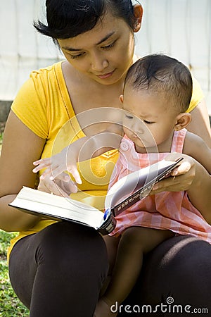 Mother reading while babysitting baby Stock Photo