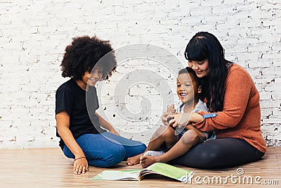Mother reading a fairy tale fable story for kids at home. African American happy family concept. Stock Photo