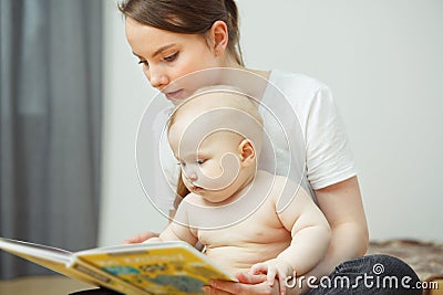 Mother reading to little infant colorful book with fairy tales. Stock Photo