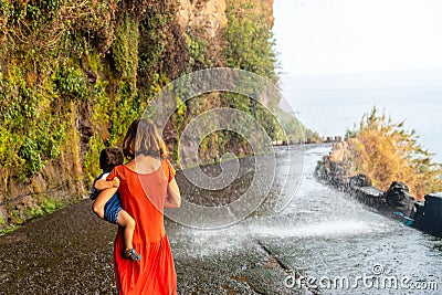 Mother in a red dress with her son at Anjos Waterfall, Madeira Stock Photo