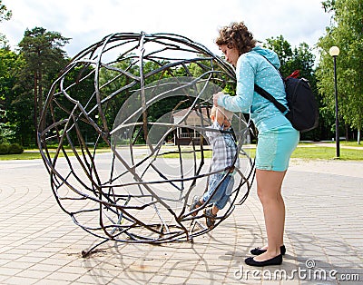 Mother rescues her little son from the sphere cage Stock Photo