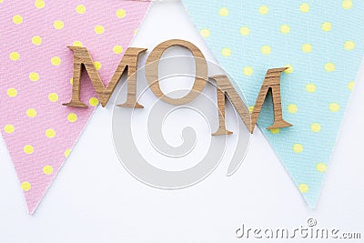 Mom wooden text on pastel fabric triangle flag on white paper texture background Stock Photo