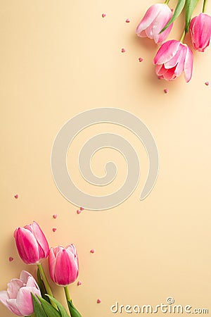 Top view vertical photo of bunches of pink tulips and heart shaped sprinkles on pastel beige background with copyspace Stock Photo