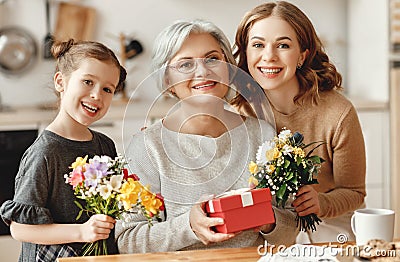 Mother`s day! three generations of family mother, grandmother and daughter congratulate on the holiday, give flowers Stock Photo