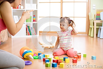 Mother see her daughter play toys messy up the living room feel angry and criticize the sadness kid girl at home. Stock Photo