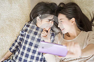 Mother is selfie with her little daughter using a smart phone camera while eye contact with daughter .Asian family concept. Stock Photo