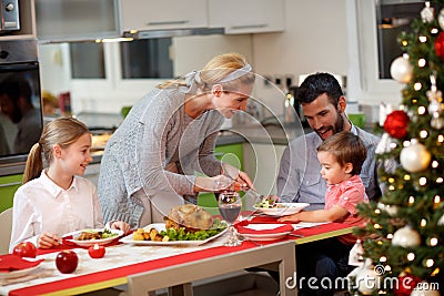 Mother serving turkey to his family in Christmas dinner Stock Photo